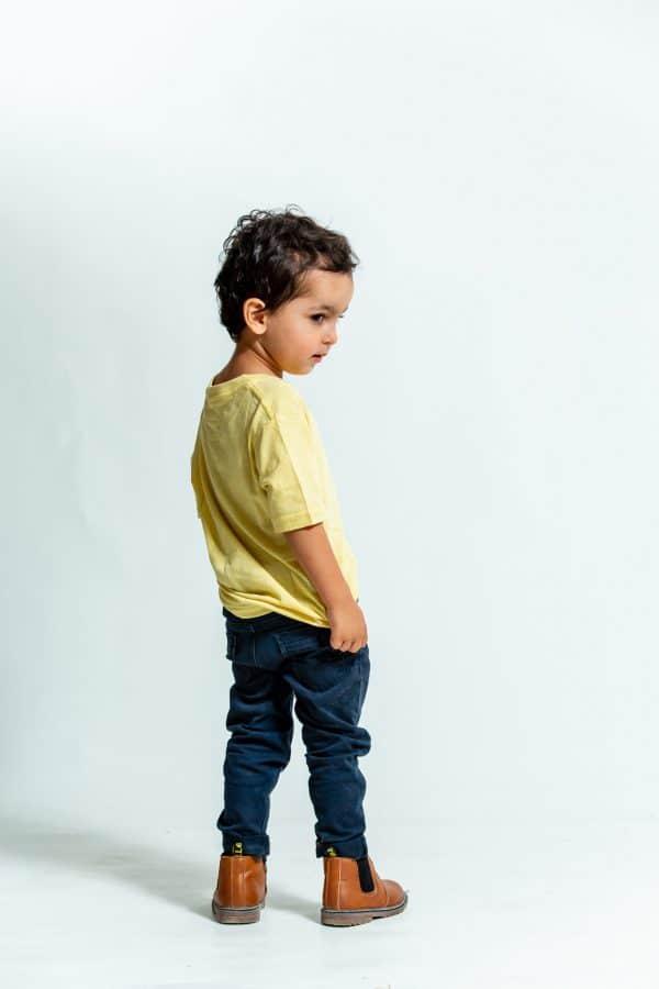 ילד עם מכנסי גינס כהים וחולצה צהובה